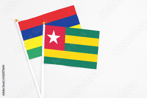Togo and Mauritius stick flags on white background. High quality fabric  miniature national flag. Peaceful global concept.White floor for copy space.