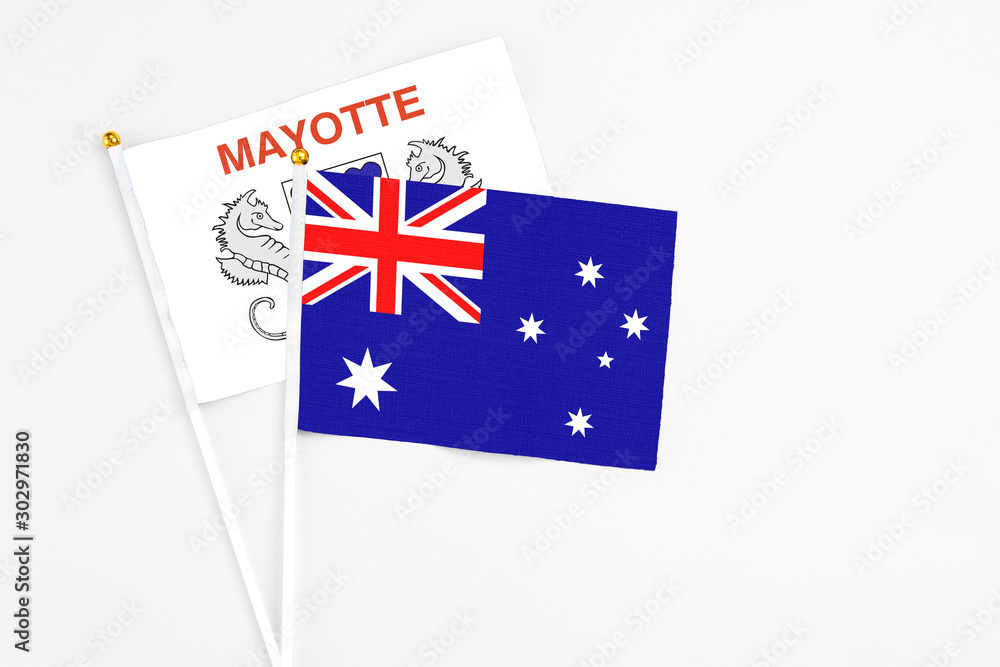 Fototapeta premium Australia and Mayotte stick flags on white background. High quality fabric, miniature national flag. Peaceful global concept.White floor for copy space.