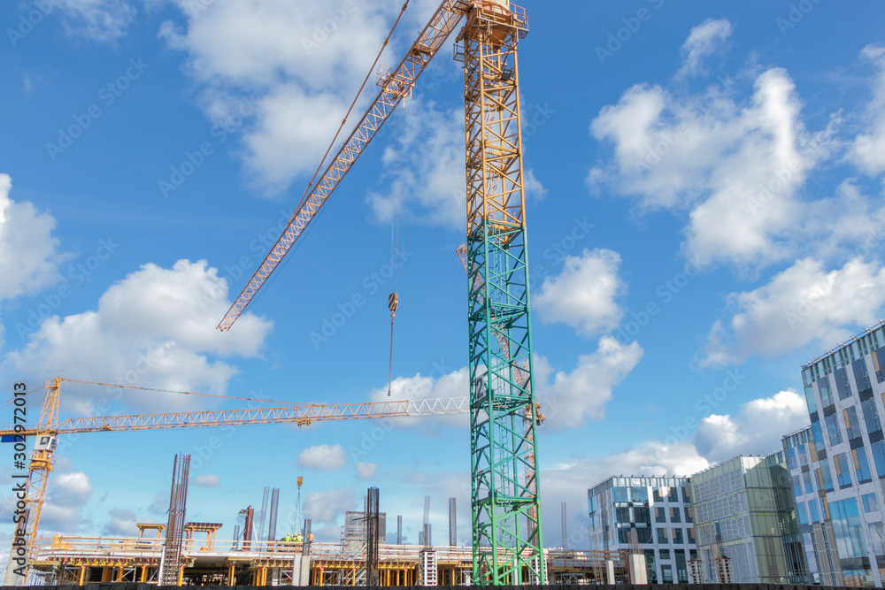 close u of construction site with crane in sunny day with blue sky and white clouds.