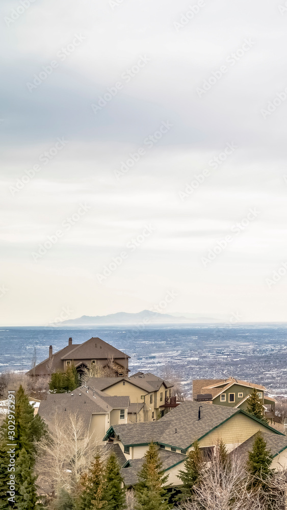Obraz premium Vertical Aerial view of houses in the valley with mountain and horizon in the distance