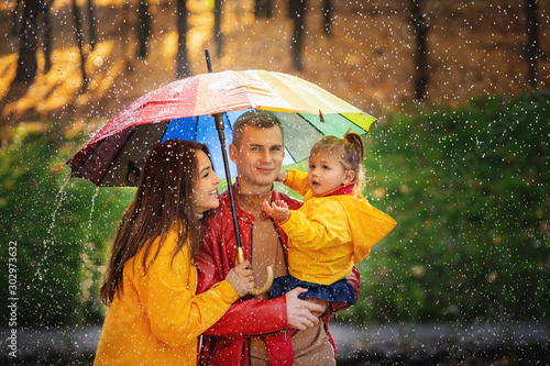 young family are enjoying rainfall. Walk in the autumn sunny park.