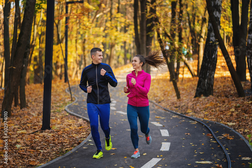 Couple jogging and running outdoors in autumn nature