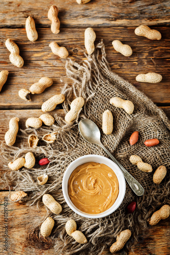 Peanut butter with peanuts on a dark wood background photo