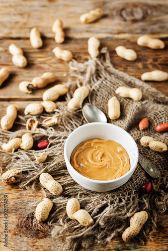 Peanut butter with peanuts on a dark wood background photo