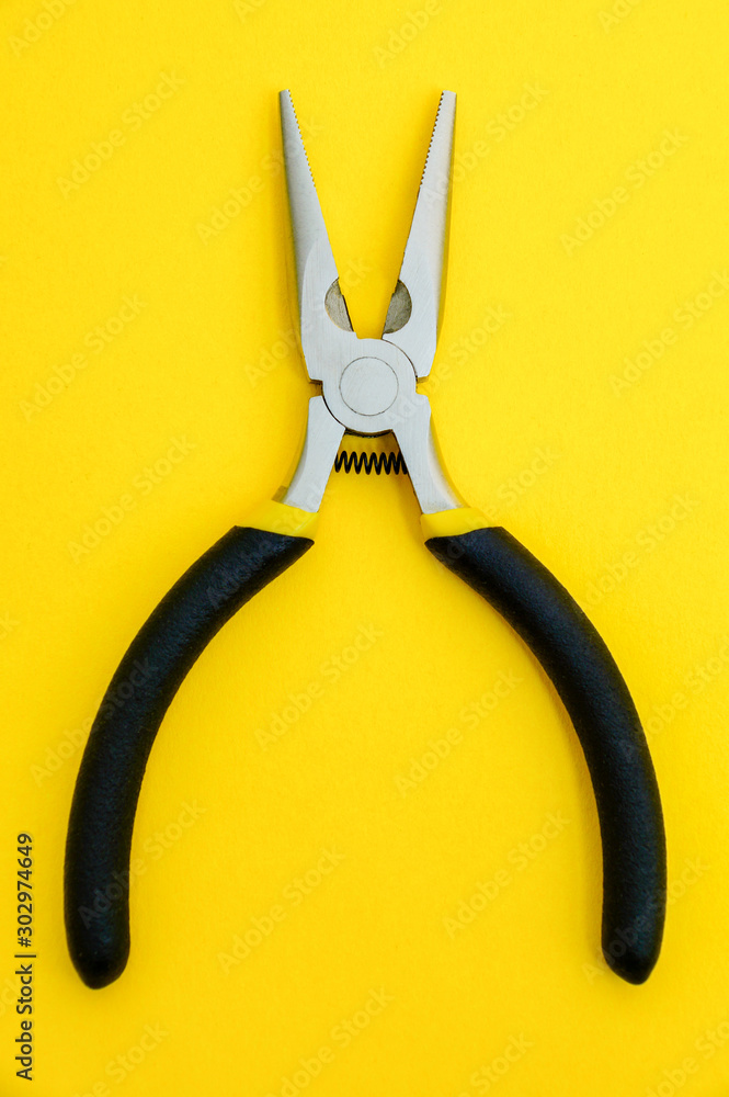 Single pliers tool with rubber handles for the master electrician on yellow background Single pliers tool with rubber handles for the master electrician on yellow background