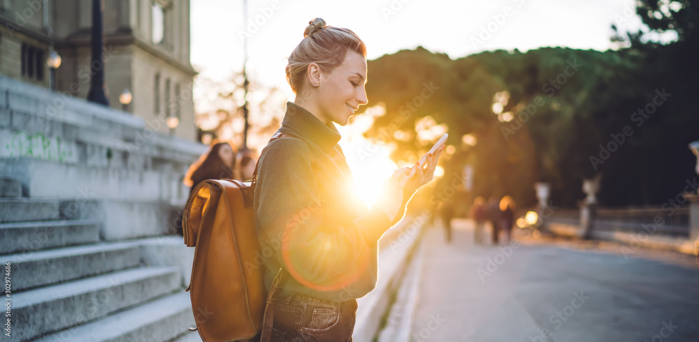 Funny hipster girl watching received video message and smiling using 4g wireless for browsing internet and send answer text via cellphone gadget, positive woman with mobile device networking
