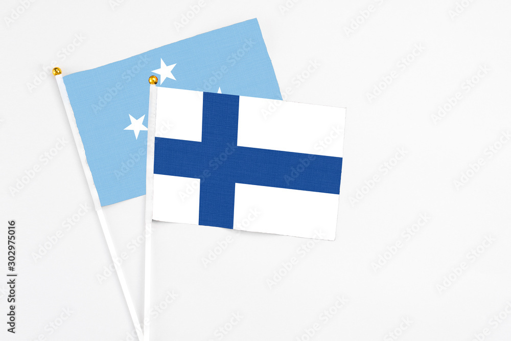 Finland and Micronesia stick flags on white background. High quality fabric, miniature national flag. Peaceful global concept.White floor for copy space.