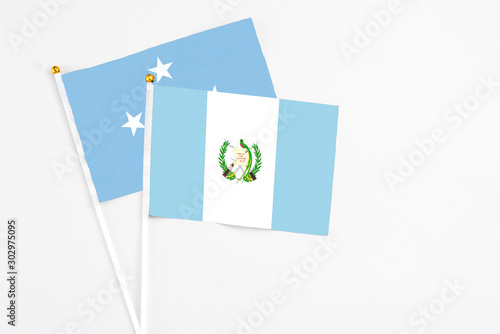 Guatemala and Micronesia stick flags on white background. High quality fabric, miniature national flag. Peaceful global concept.White floor for copy space.