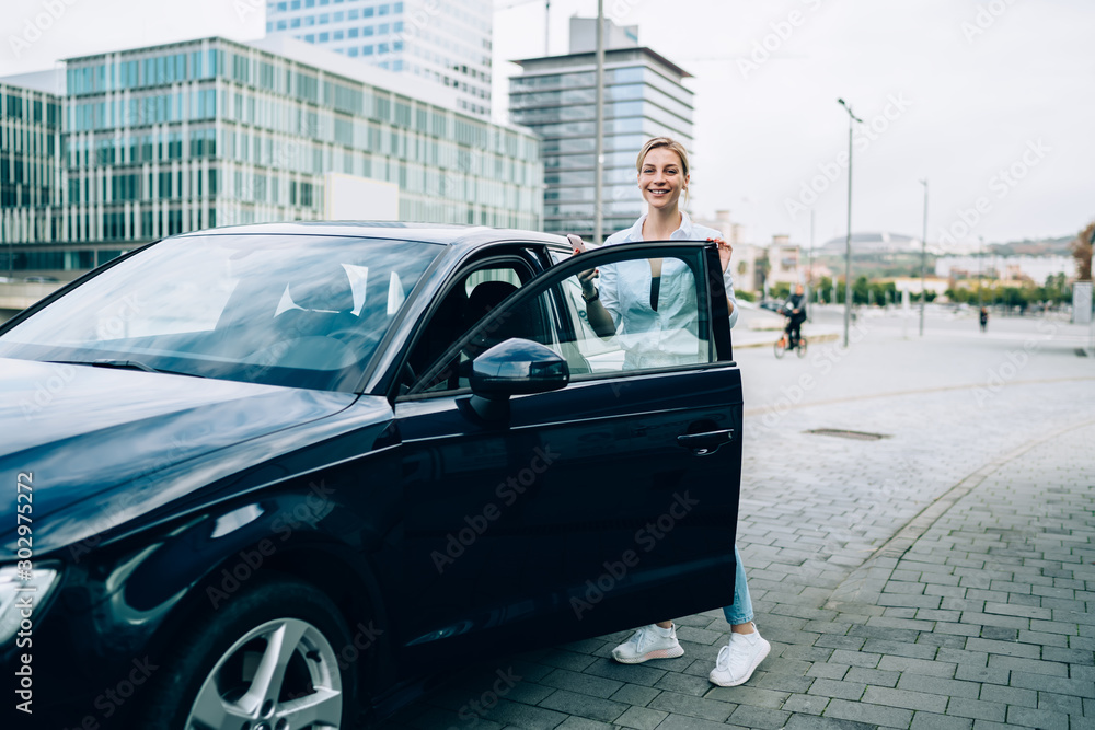 Fototapeta premium Young casual woman with car on street sidewalk