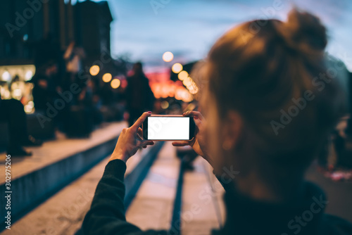 Female photographer standing on stairs and taking picture of street