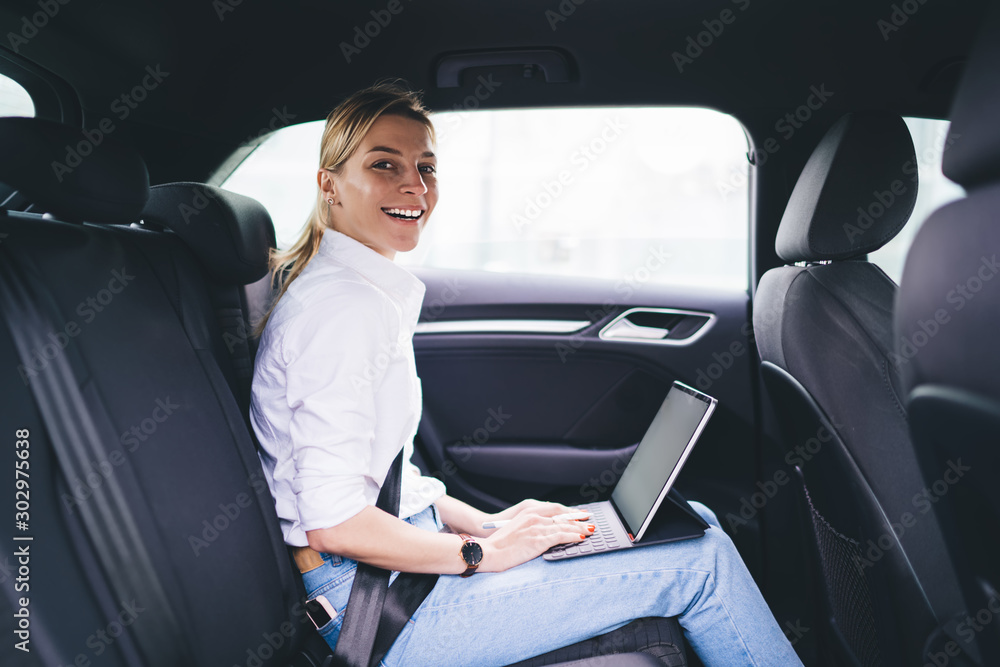 Businesswoman browsing on tablet on car back seat