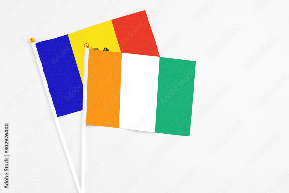 Cote D'Ivoire and Moldova stick flags on white background. High quality fabric, miniature national flag. Peaceful global concept.White floor for copy space.