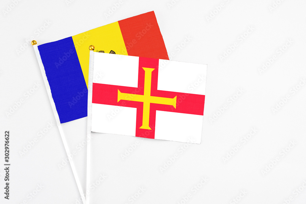 Guernsey and Moldova stick flags on white background. High quality fabric, miniature national flag. Peaceful global concept.White floor for copy space.
