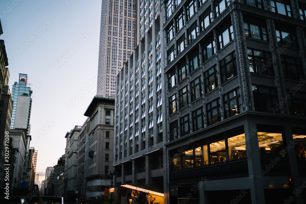 Evening view of tall building exterior with real estate for commercial and residential rent in midtown, urban architecture with high skyscrapers and old construction fronts on street in New York