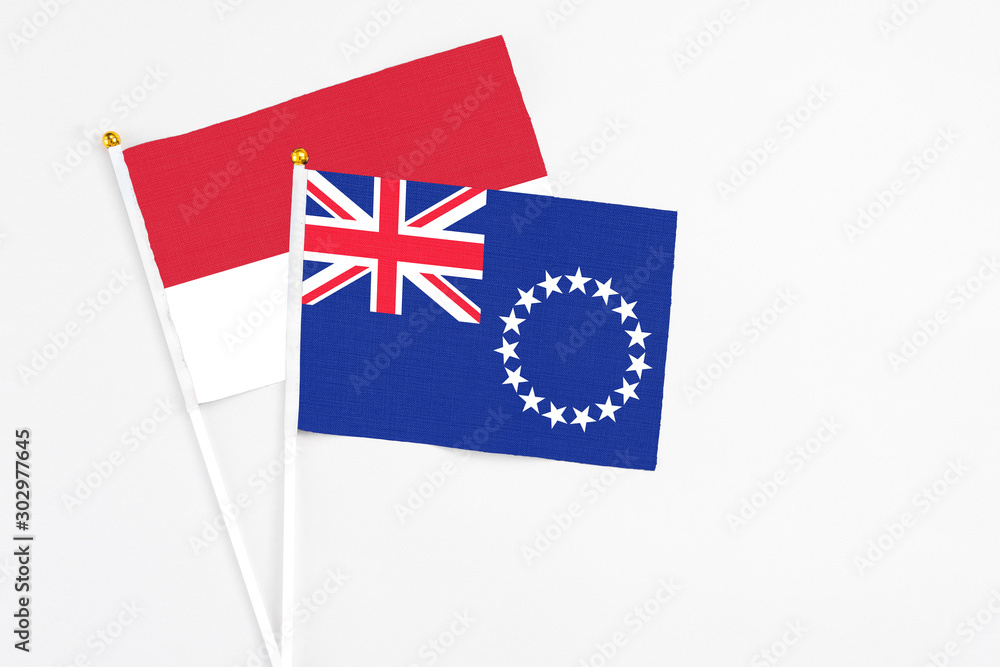 Fototapeta premium Cook Islands and Monaco stick flags on white background. High quality fabric, miniature national flag. Peaceful global concept.White floor for copy space.
