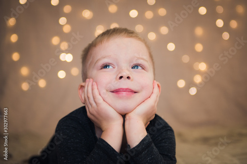 happy boy on lights garland background, indoor christmas portrait
