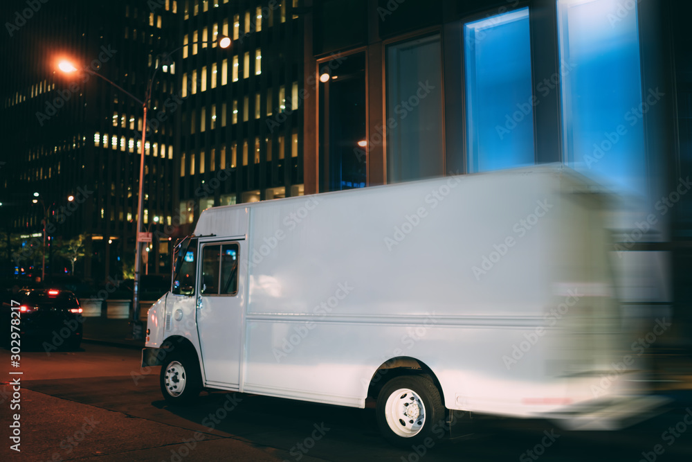 Van automobile driving fast in evening downtown transporting and distributing goods for delivery service, mock up copy space on cargo body for logistic company name or logo of startup business