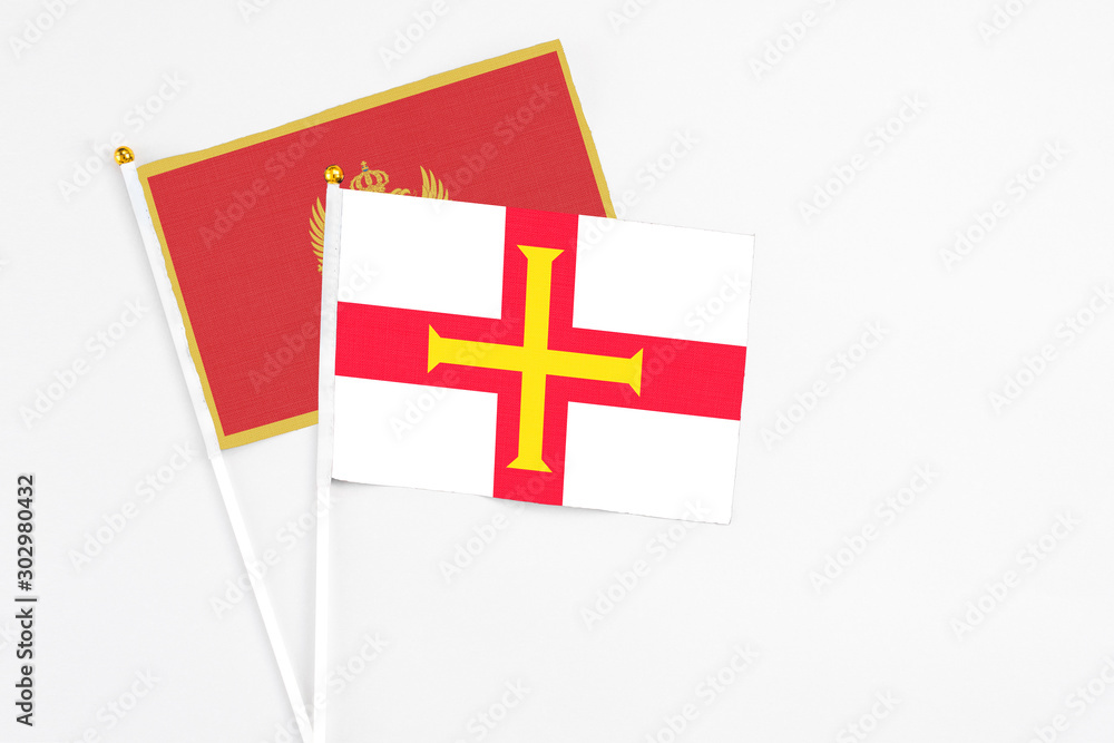 Guernsey and Montenegro stick flags on white background. High quality fabric, miniature national flag. Peaceful global concept.White floor for copy space.
