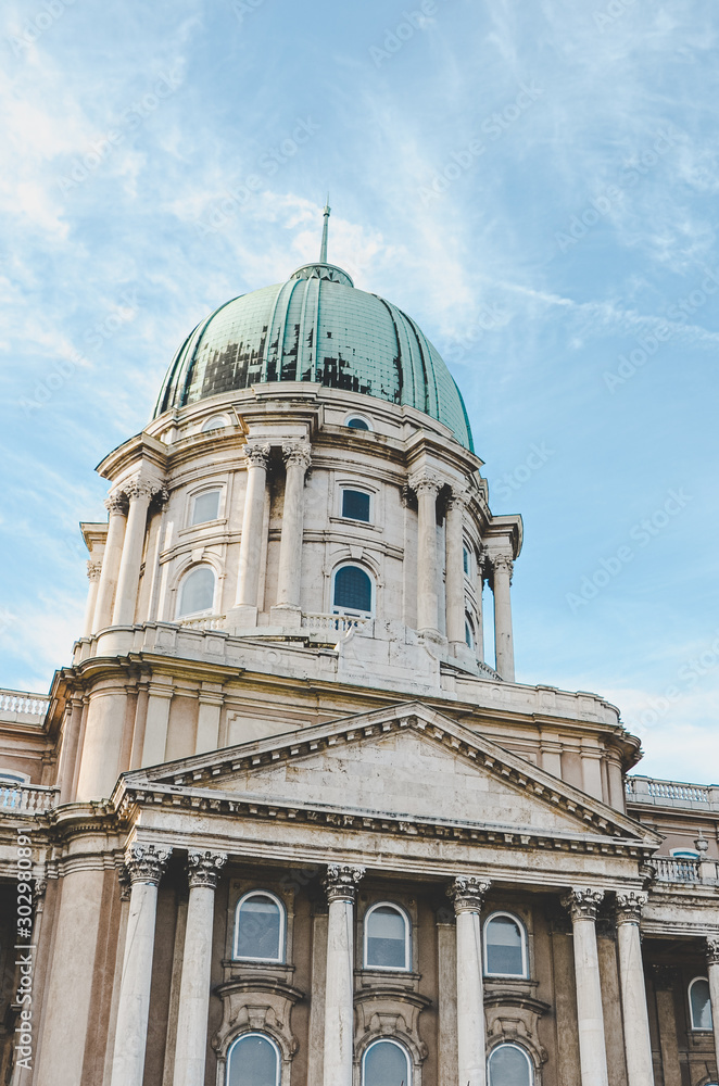 Cupola of the Buda Castle in Budapest, Hungary on vertical photo. Bottom view against the light sky. Historical castle and palace complex of the Hungarian kings. Facade with pillars and cupola