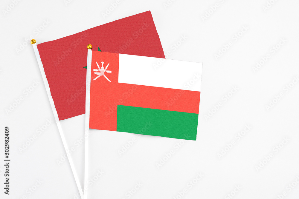 Oman and Morocco stick flags on white background. High quality fabric, miniature national flag. Peaceful global concept.White floor for copy space. Oman and Morocco stick flags on white background. High quality fabric, miniature national flag. Peaceful global concept.White floor for copy space.