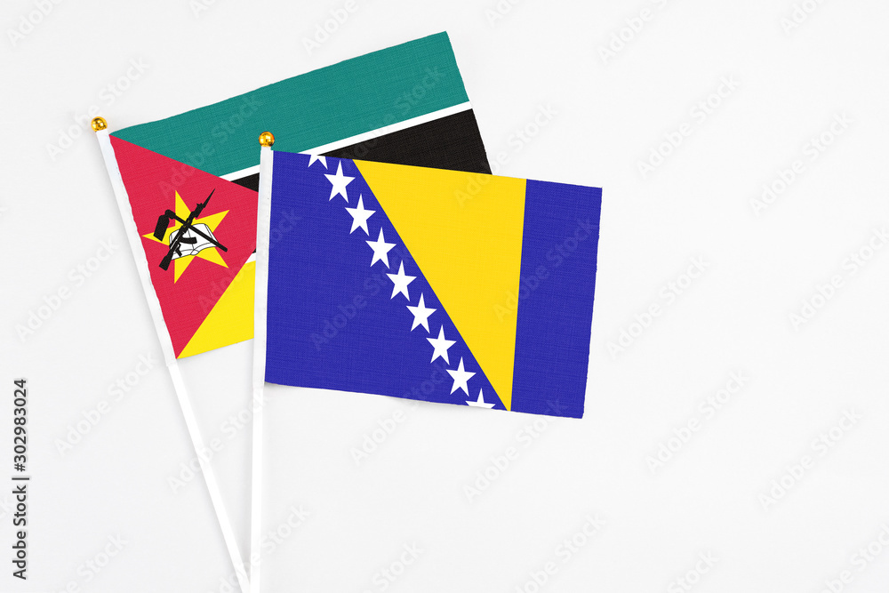 Fototapeta premium Bosnia Herzegovina and Mozambique stick flags on white background. High quality fabric, miniature national flag. Peaceful global concept.White floor for copy space.