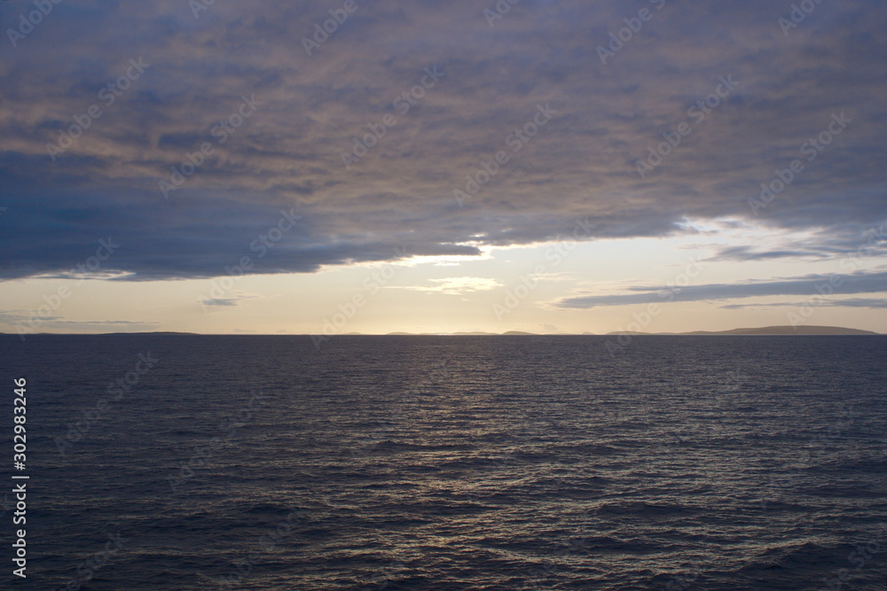 Image of the sunset hidden by clouds over the sea