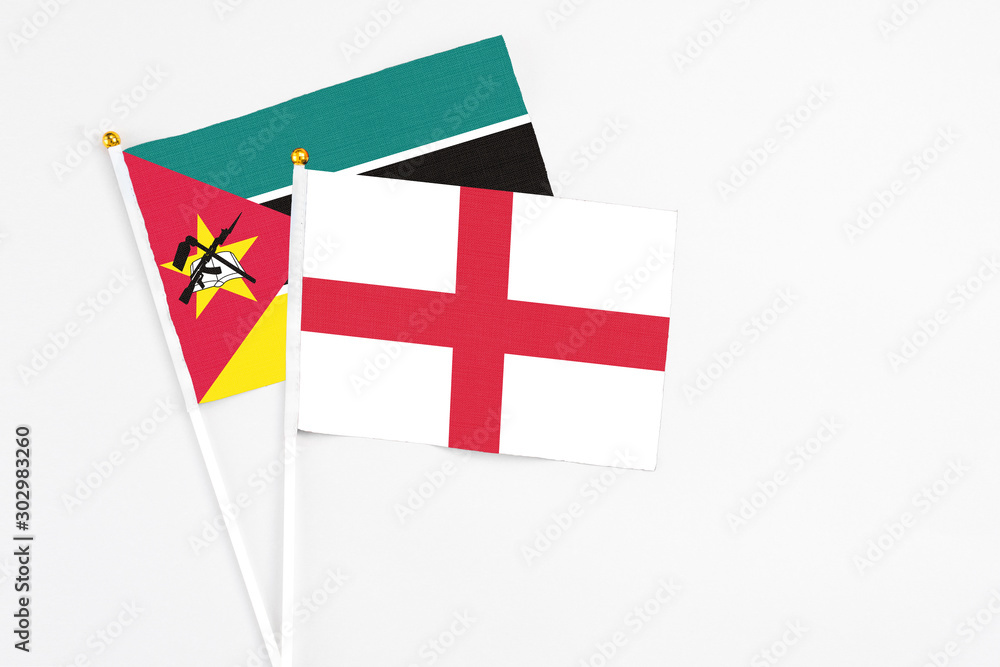 England and Mozambique stick flags on white background. High quality fabric, miniature national flag. Peaceful global concept.White floor for copy space.