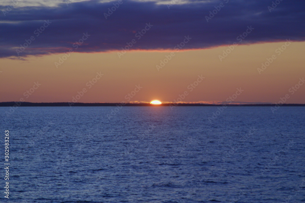 Fototapeta premium Image of the sun setting in the sea behind the island
