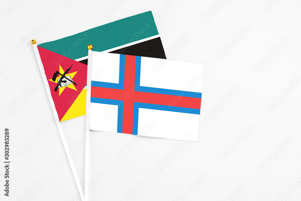 Faroe Islands and Mozambique stick flags on white background. High quality fabric, miniature national flag. Peaceful global concept.White floor for copy space.