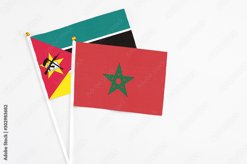 Morocco and Mozambique stick flags on white background. High quality fabric, miniature national flag. Peaceful global concept.White floor for copy space. Morocco and Mozambique stick flags on white background. High quality fabric, miniature national flag. Peaceful global concept.White floor for copy space.