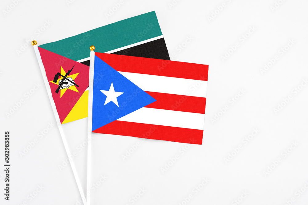 Puerto Rico and Mozambique stick flags on white background. High quality fabric, miniature national flag. Peaceful global concept.White floor for copy space. Puerto Rico and Mozambique stick flags on white background. High quality fabric, miniature national flag. Peaceful global concept.White floor for copy space.
