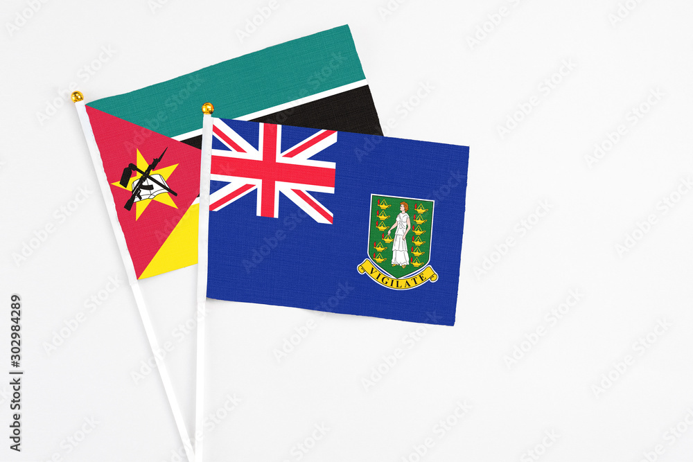 Fototapeta premium British Virgin Islands and Mozambique stick flags on white background. High quality fabric, miniature national flag. Peaceful global concept.White floor for copy space.