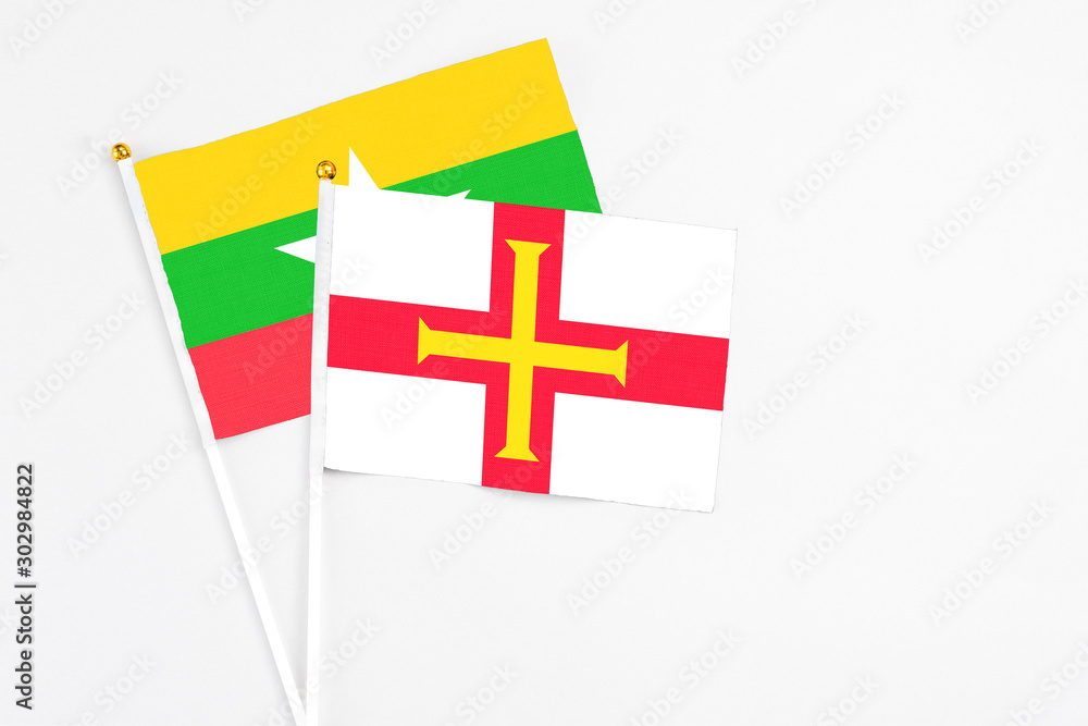 Guernsey and Myanmar stick flags on white background. High quality fabric, miniature national flag. Peaceful global concept.White floor for copy space.