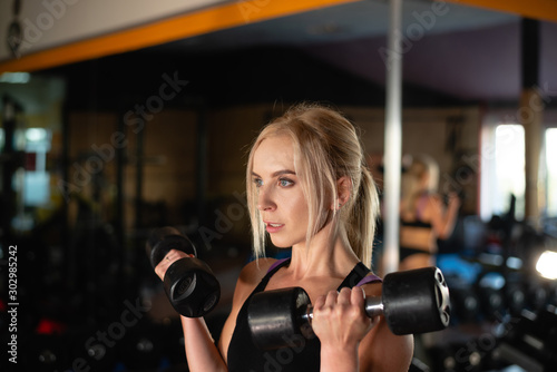 Fitness woman during training, exercises for arms, dumbbells in hands