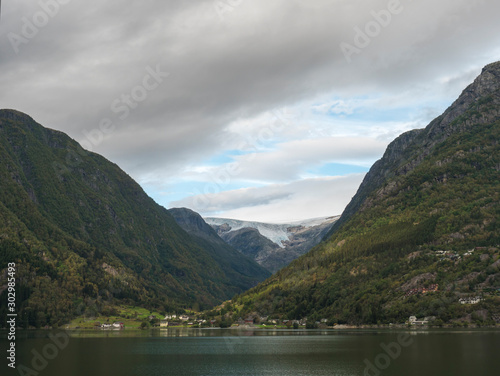 View over blue water of Hardanger Fjord in Kinsarvik on folgefonna glacier with small village on the coast. Norway nature and travel background. Early autumn day.