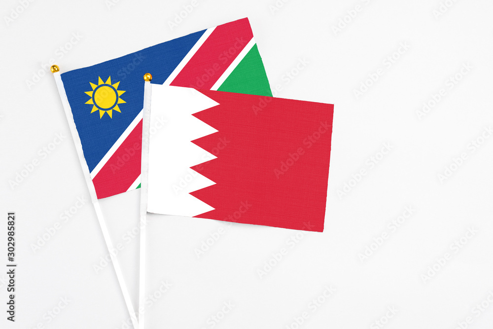 Obraz premium Bahrain and Namibia stick flags on white background. High quality fabric, miniature national flag. Peaceful global concept.White floor for copy space.