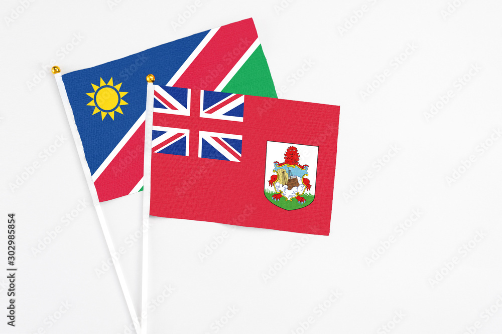 Fototapeta premium Bermuda and Namibia stick flags on white background. High quality fabric, miniature national flag. Peaceful global concept.White floor for copy space.