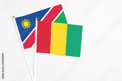 Guinea and Namibia stick flags on white background. High quality fabric, miniature national flag. Peaceful global concept.White floor for copy space.