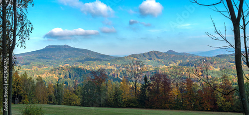 Luzicke hory panorama, meadow with autumn colorful forest and trees and hills with lookout tower on hill Hochwald Hvozd and blue sky landscape in luzicke hory mountain. photo