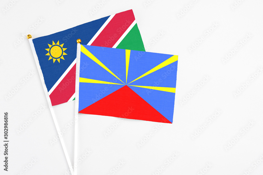 Reunion and Namibia stick flags on white background. High quality fabric, miniature national flag. Peaceful global concept.White floor for copy space.