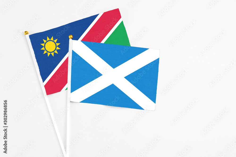 Obraz premium Scotland and Namibia stick flags on white background. High quality fabric, miniature national flag. Peaceful global concept.White floor for copy space.