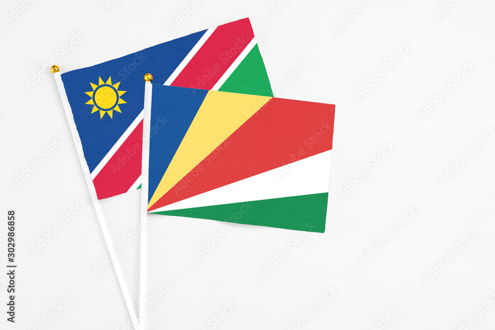 Seychelles and Namibia stick flags on white background. High quality fabric, miniature national flag. Peaceful global concept.White floor for copy space. Seychelles and Namibia stick flags on white background. High quality fabric, miniature national flag. Peaceful global concept.White floor for copy space.