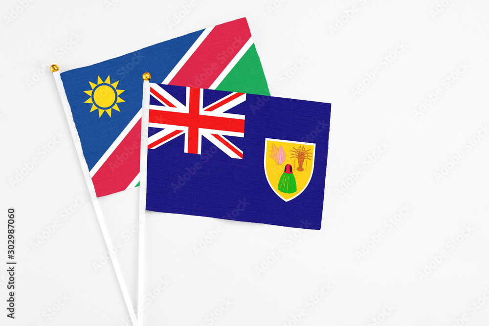 Turks And Caicos Islands and Namibia stick flags on white background. High quality fabric, miniature national flag. Peaceful global concept.White floor for copy space. Turks And Caicos Islands and Namibia stick flags on white background. High quality fabric, miniature national flag. Peaceful global concept.White floor for copy space.