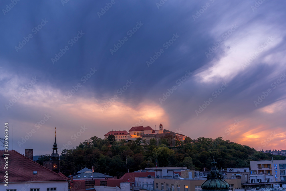 Castle Spilberk Brno city slow moving clouds captured just from castle turn public light on going from blue hour to night time with colored sky and clouds.