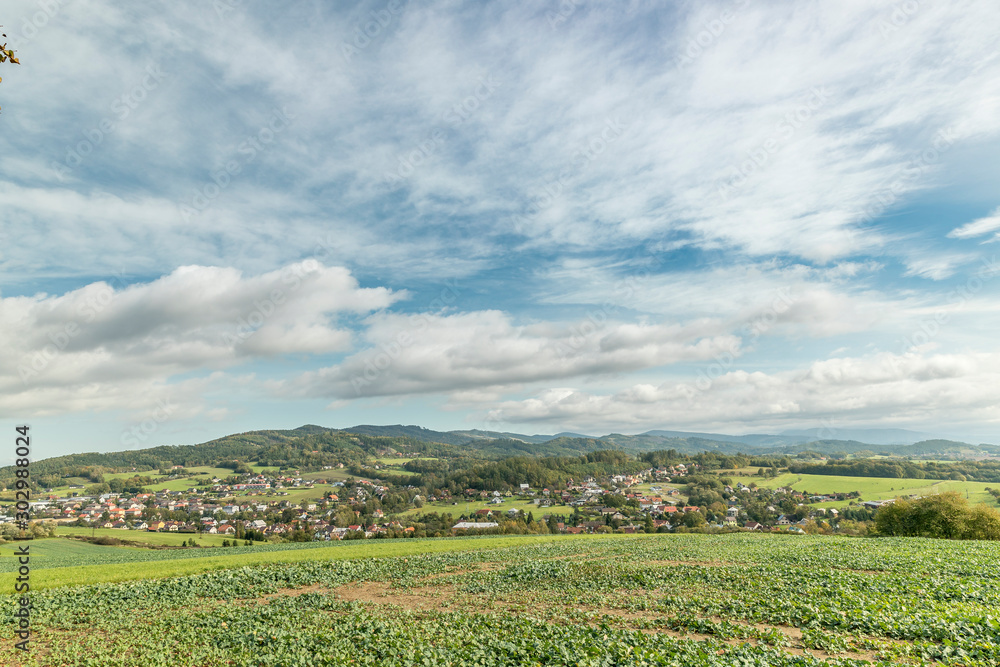 Moving clouds in two directions, above the village of the Krhova Beskydy Czech republic looking at horizon around with visible hills and mountains during sunny days and field for crop