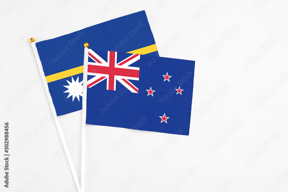 Fototapeta premium New Zealand and Nauru stick flags on white background. High quality fabric, miniature national flag. Peaceful global concept.White floor for copy space.