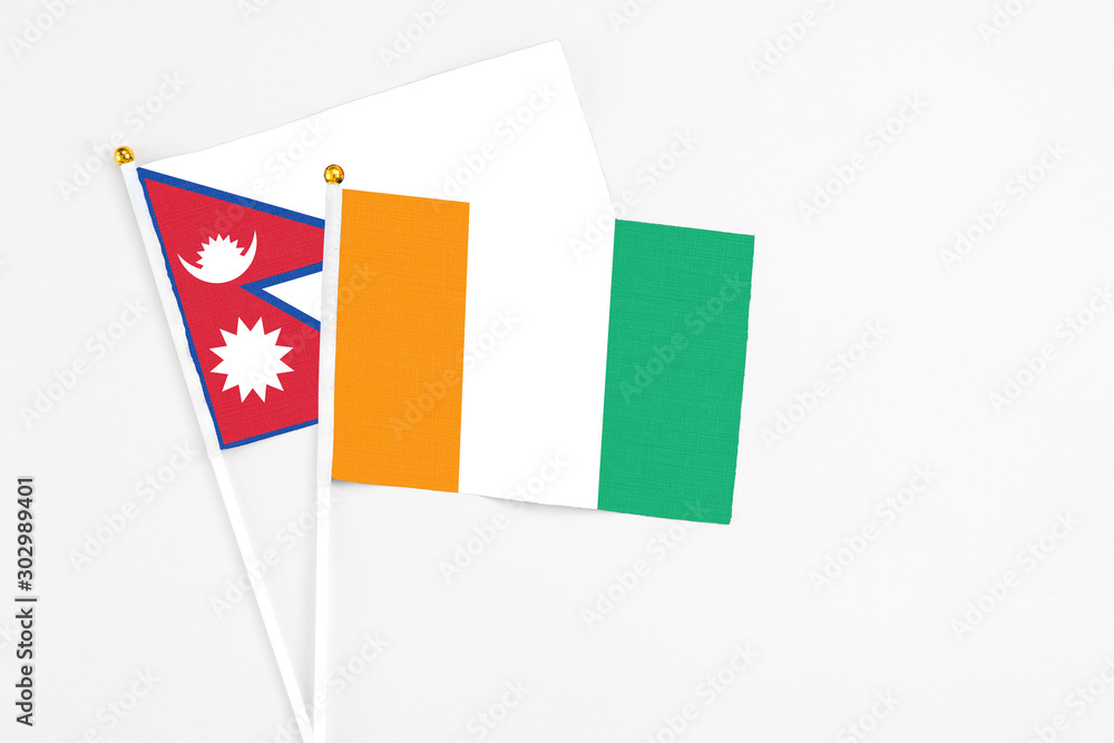 Cote D'Ivoire and Nepal stick flags on white background. High quality fabric, miniature national flag. Peaceful global concept.White floor for copy space. Cote D'Ivoire and Nepal stick flags on white background. High quality fabric, miniature national flag. Peaceful global concept.White floor for copy space.