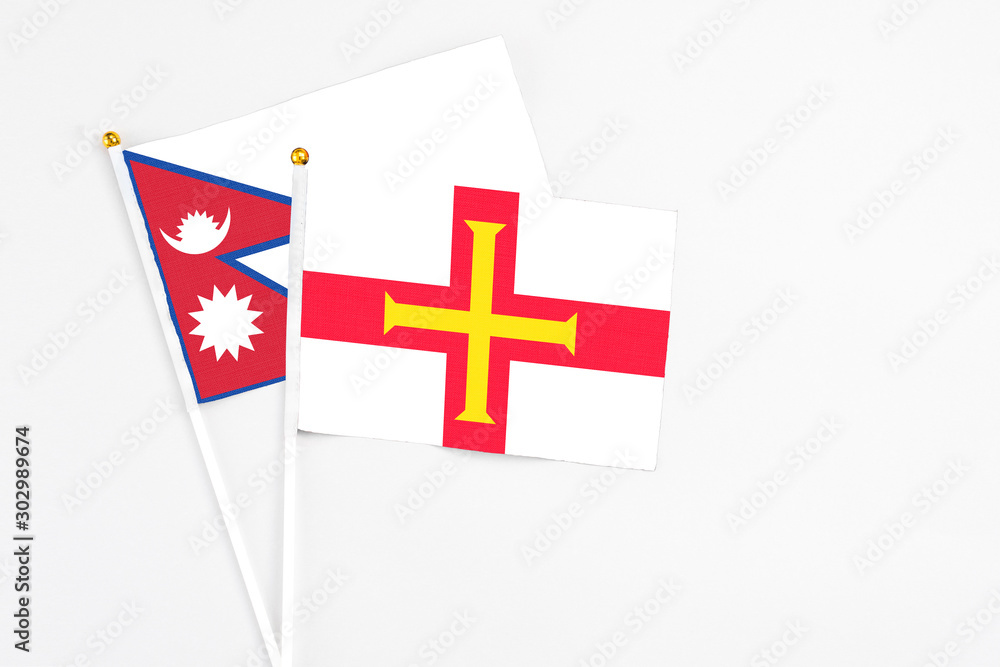 Guernsey and Nepal stick flags on white background. High quality fabric, miniature national flag. Peaceful global concept.White floor for copy space.