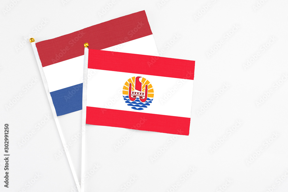 French Polynesia and Netherlands stick flags on white background. High quality fabric, miniature national flag. Peaceful global concept.White floor for copy space. French Polynesia and Netherlands stick flags on white background. High quality fabric, miniature national flag. Peaceful global concept.White floor for copy space.