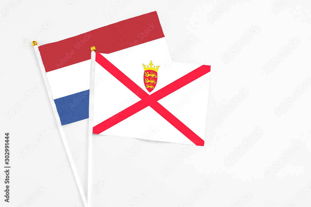 Jersey and Netherlands stick flags on white background. High quality fabric, miniature national flag. Peaceful global concept.White floor for copy space.